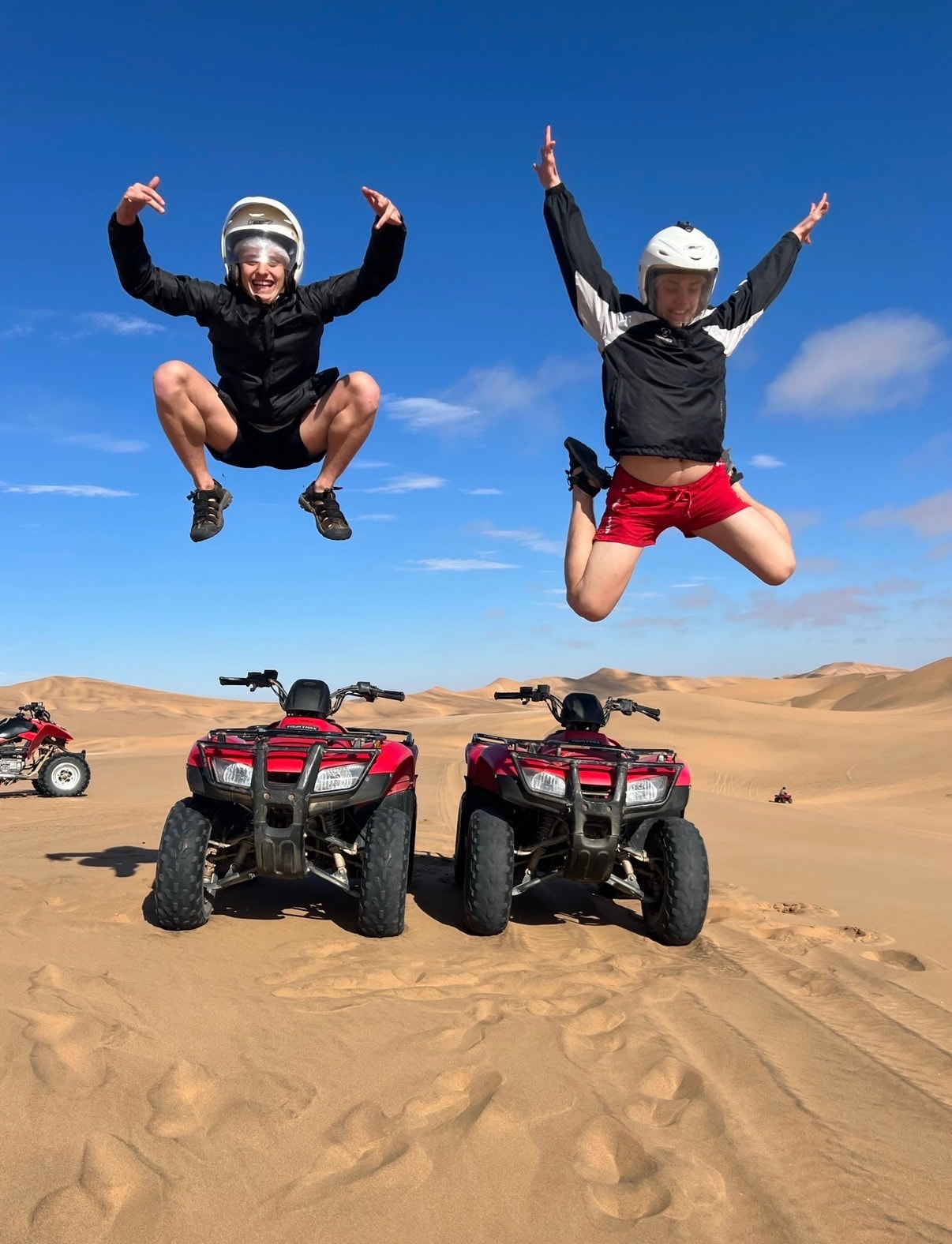 Jumping above quad bikes in desert dunes