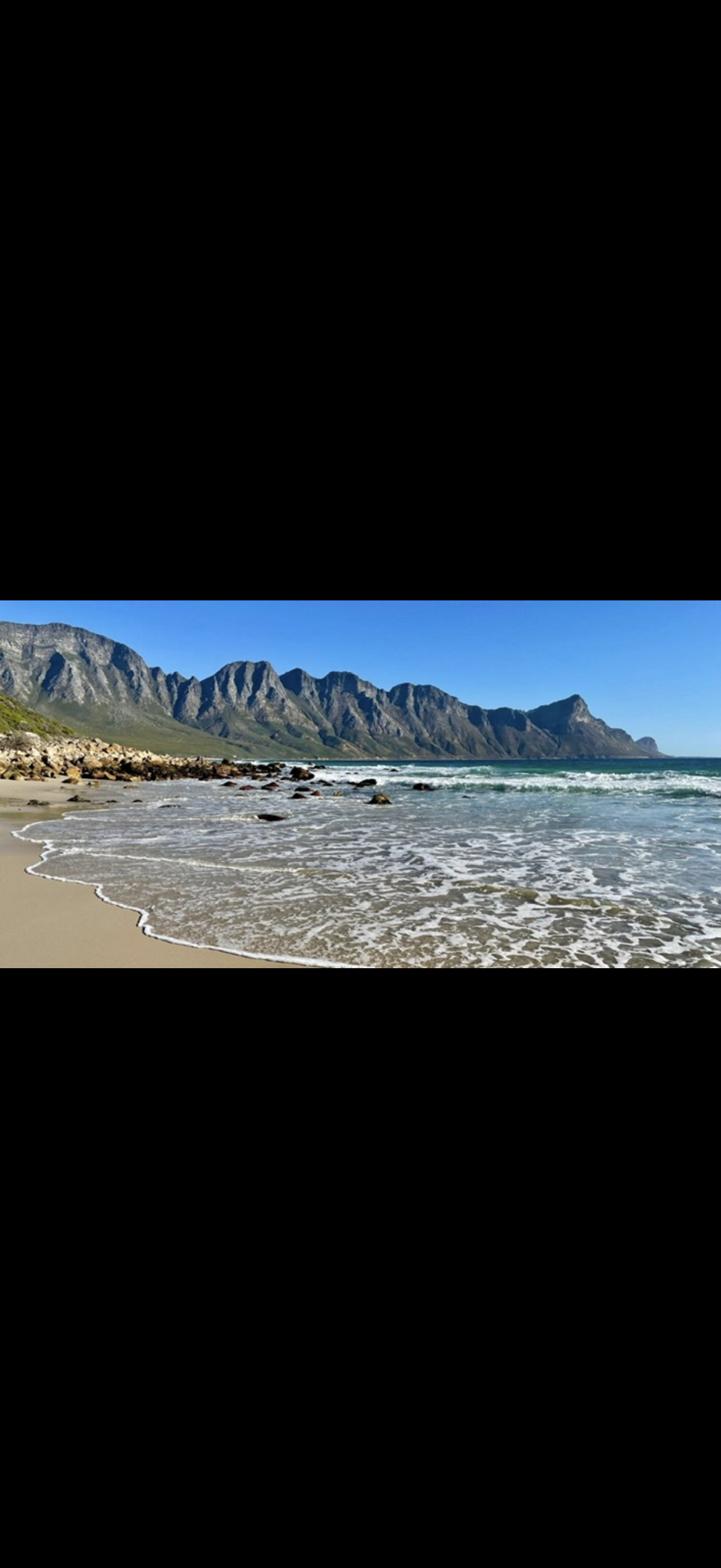 Coastal beach with dramatic mountain backdrop